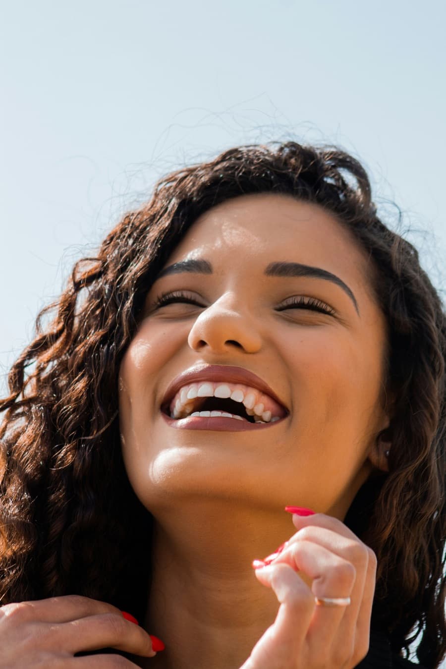Mulher sorrindo ao ar livre, com os dentes à mostra
